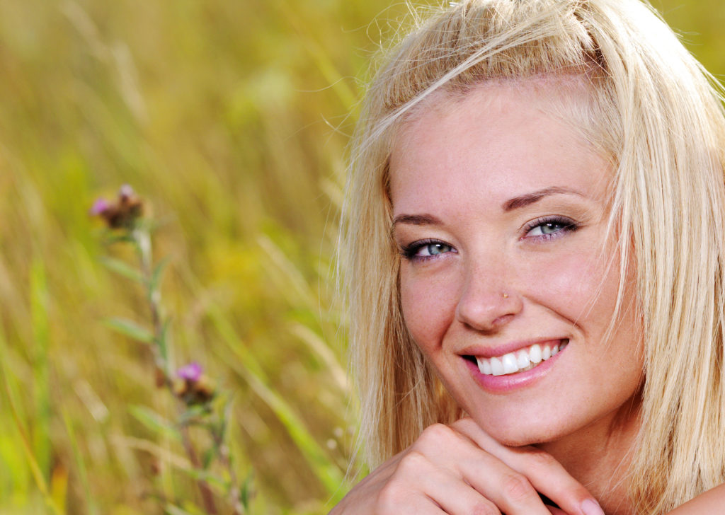 A smiling woman in a field | Xeomin Treatments at NYMIS