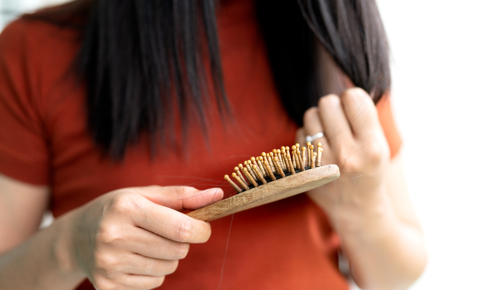 Woman looking at a hair brush to help illustrate Hair Loss After Weight Loss Surgery